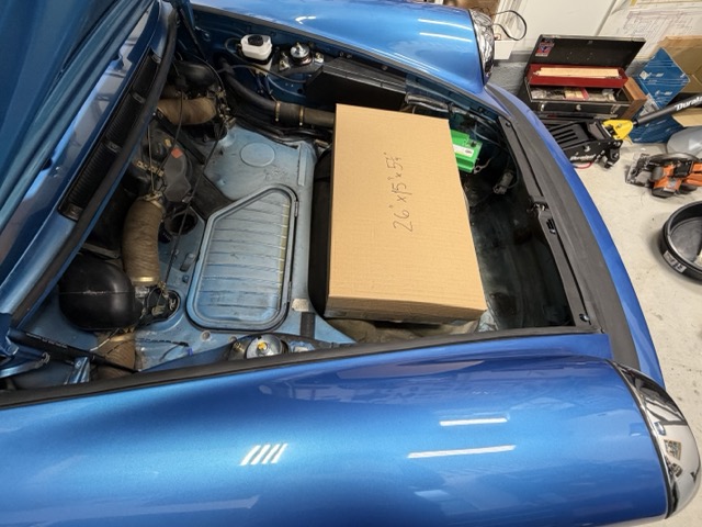 Cardboard battery mockup positioned in the front compartment of the Porsche 912E